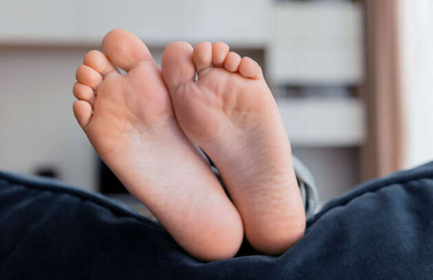 Imagem dos pés apoiado no encosto do sofá