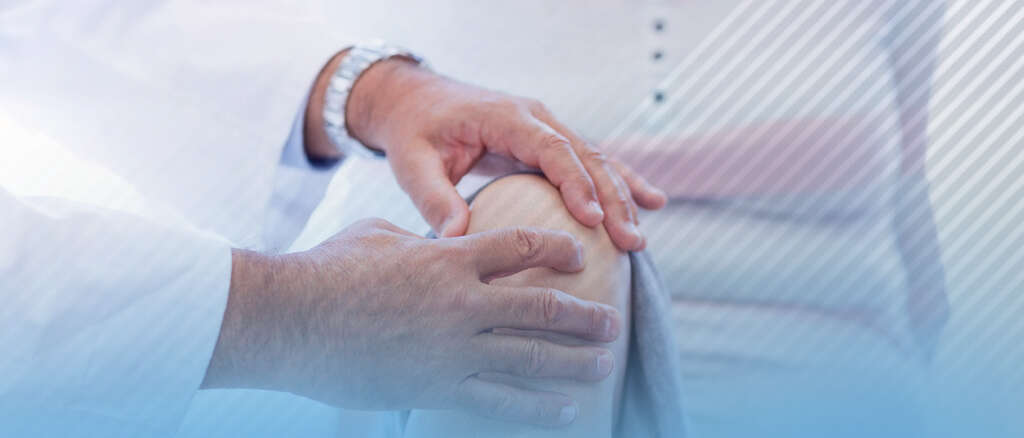 Imagem de duas mãos tocando o ombro de um paciente. A especialidade desse médico é ortopedia.